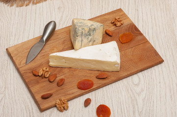 Brie cheese on a board with honey, nuts, dried apricots, grapes