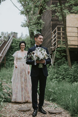 Smiling bride and groom spending time together. Posing on the mountain hills background. Dressed in white dress beautiful blonde caucasian bride and handsome groom. Hugs, kissess and enjoy the company