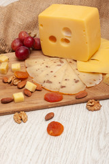 sliced walnut cheese on a board, grapes, dried apricots and nuts