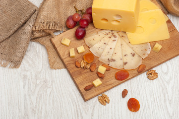 sliced walnut cheese on a board, grapes, dried apricots and nuts