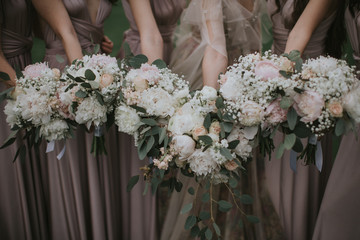 Wedding bride bouquet. Bridesmaids holding pastel flower bouquet in their hands. Bridesmaids and bride dressed in soft berry dress