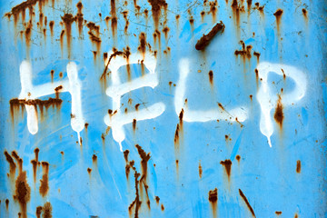 Blue metal surface with brown rusted spots and text help in white. Urban graffiti background.