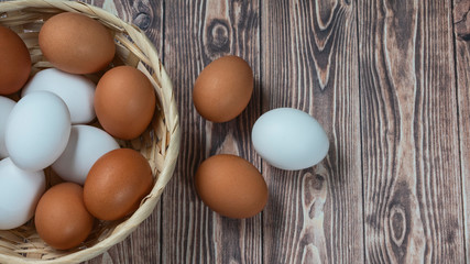 several fresh chicken eggs in a straw basket on a wooden background. Healthy eating concept