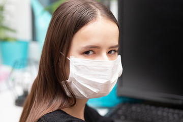 Danger of virus infection. Young woman in antibacterial mask at work in the office.