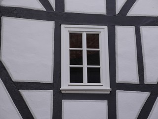 Details of a half-timbered house with a lattice window, over the centuries the beams have crooked. White stone wall, black wood, the grain can be seen beautifully