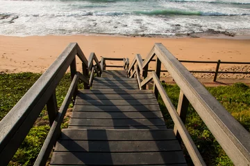 Foto op Plexiglas Afdaling naar het strand Houten trap boven vegetatie die naar het strand leidt