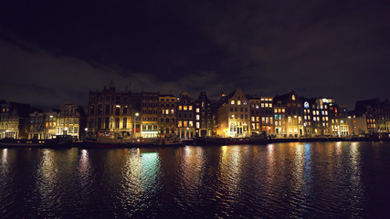 Fototapeta na wymiar Canal of Amsterdam at night with reflection of illuminated houses in water, Netherlands. Beautiful old European city view.