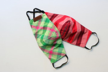 Two handmade face masks made from plaid cloth placed on wooden table, washable and reusable, can be...