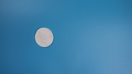 New cotton pad for removing makeup on a blue background with place for text