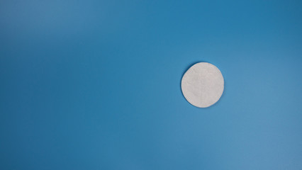 New cotton pad for removing makeup on a blue background with place for text