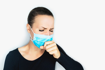 Young sick, a woman in  protective mask on her face coughs, holding hands into a fist, suffers from cough, sore throat on a white background. Cold, Chinese coronavirus virus, flu, illness concept.