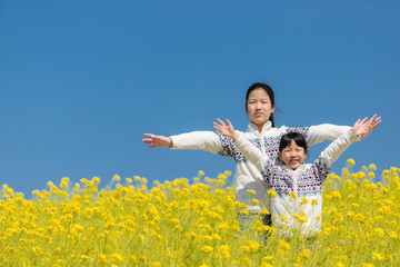 春の満開の菜の花畑で遊んでいる子供姉妹