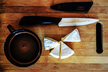 Camembert creamy soft cheese and a cup of black strong coffee on a wooden background. Breakfast