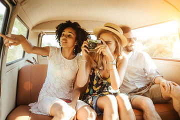 Three best friends travel in a minivan bus and explore new places. Two girls and one boy having...