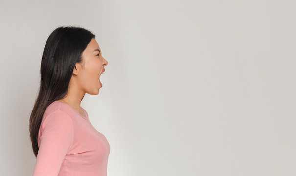 Side view of asian girl screaming towards copy space