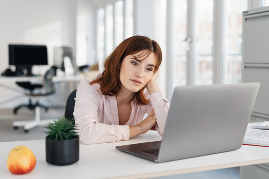 Young businesswoman sitting staring at a laptop