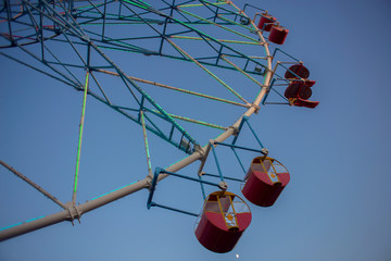 Ferris wheel carousel in an amusement park at sunset. Seating on a swing. Entertain people on...