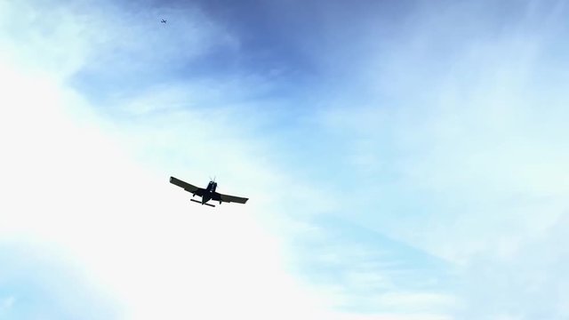 Small plane landing in slow motion against a bright blue sky.