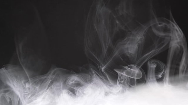 Texture of cigarette white smoke on a black background. Slow motion. Vape smoke.