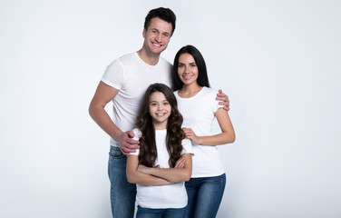 Beautiful excited and the funny family team is posing and pointing in a white t-shirt while they isolated on white background in studio.