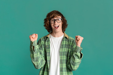 Victory and success concept. Excited millenial guy showing YES gesture on turquoise background