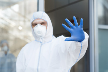 Man in virus protective suit and mask gesturing to stop world epidemic