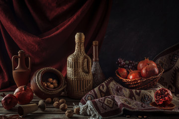 Obraz na płótnie Canvas Still life with pomegranates and walnuts. Oriental flavor. Horizontal format. Ceramic jugs with wine.
