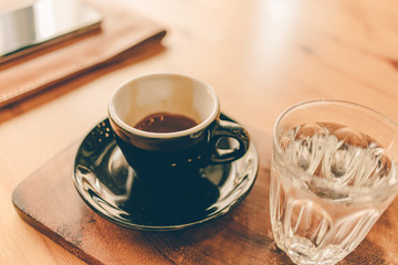 Set of espresso coffee cup with a glass of water on wooden table.