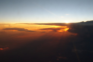 Fototapeta na wymiar mysterious sunset with clouds from the airplane window with
