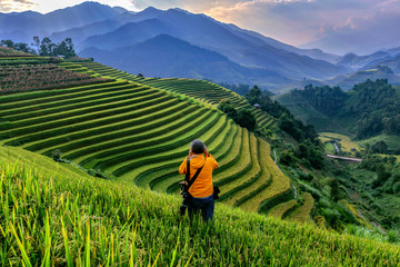 Fototapeta premium The photographer is standing to take pictures of the beautiful rice terraces in Mu cang chai , northern Vietnam.