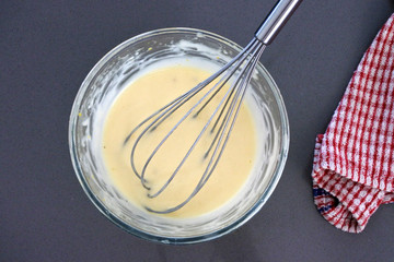 Homemade Mayonnaise souce in a glass bowl with whisk utensil tool