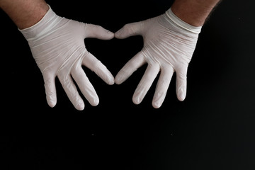 Two hands in medical gloves show heart shape