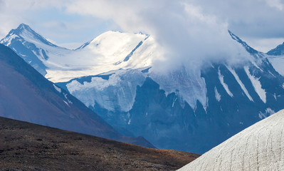 Snow-capped mountain peaks rise above the clouds