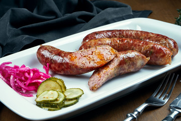 Appetizing juicy pork minced sausage baked in a smoker with cheddar in a white plate with canned vegetables. German beer snack