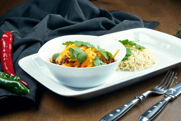 Traditional Mexican cuisine dish - chili con carne. spicy stew containing chili peppers,meat and tomatoes and beans with cheddar and rice