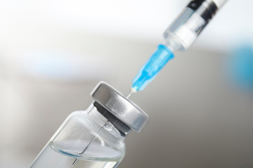 Vial and syringe on blurred background. Vaccination and immunization