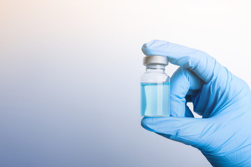 Doctor holding vial with medication on light background, closeup view and space for text....