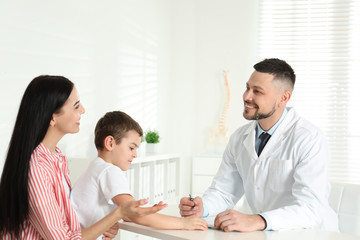 Fototapeta premium Little boy with mother visiting orthopedist at clinic