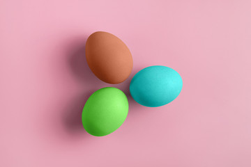 Three fresh coloured chicken eggs on a pink background. Minimal Happy Easter concept decoration.