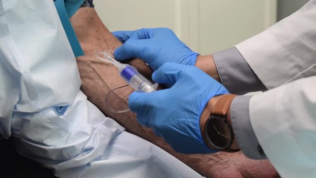 Medical Doctor Drawing Blood Sample with Syringe White Labcoat Blue Gloves