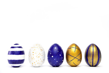 Five easter eggs trendy colored classic blue, white and golden decorated on white table. Happy Easter card with copy space for text. Minimal style.