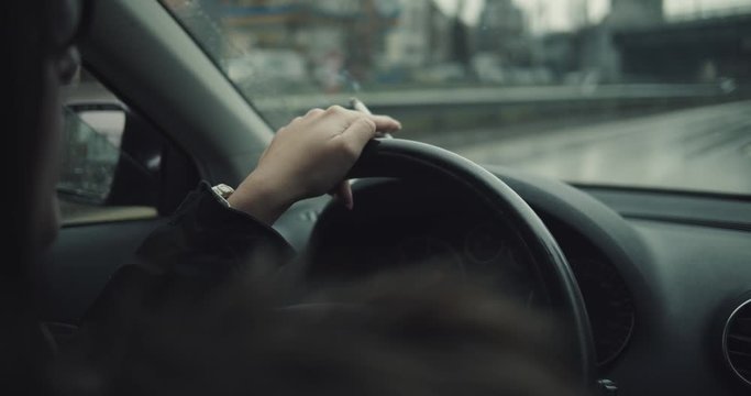 women smoke cigarette and drives in city on a cloudy day and raindrop fall front window