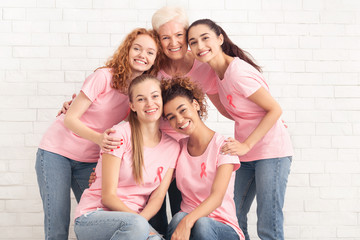 Volunteers In T-Shirts With Pink Ribbons Embracing Over White Wall