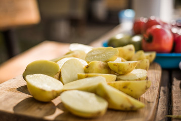 Sliced up raw potatoes. Fresh potatoes on table. Apples in background.