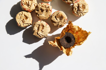 Puerh tea in craft paper packaging on white background at sunny day. Trendy minimal chinese drink concept 