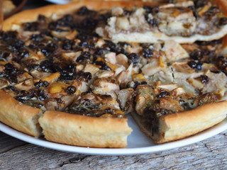 Sweet cake with nightshade berries and apples covered with beaten eggs on a wooden background.Homemade cake.