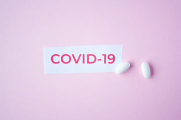 The inscription quote covid-19 on a blue background with two white tablets next to it. Coronavirus treatment concept. Medicines, vaccine for the virus.