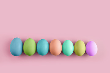 Seven coloured chicken eggs in row on a pink background. Minimal Happy Easter concept decoration. Copy space for text mockup.