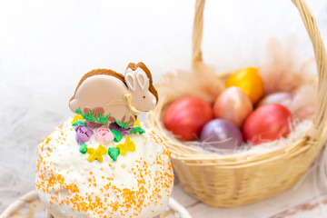 Fototapeta na wymiar Easter holiday. Colored eggs in a basket. Easter gingerbread bunny on the sandwich. on a light wooden background.