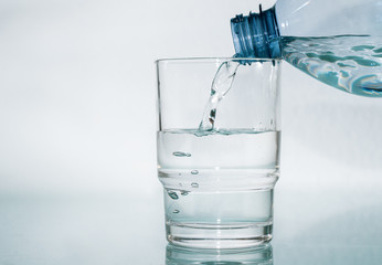 Wasser aus Flasche in das Glas giessen - Plastikflasche